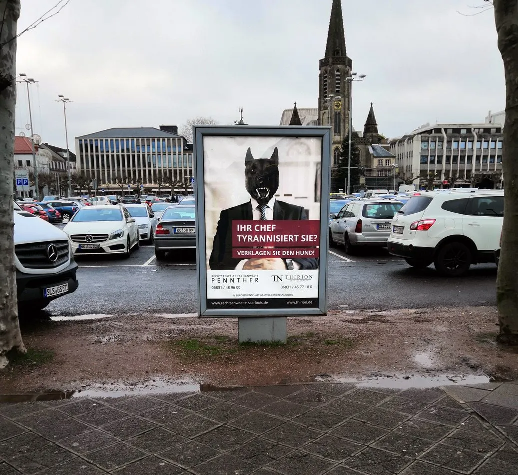 Plakat der Kanzlei Thirion auf einem Parkplatz in der Stadt